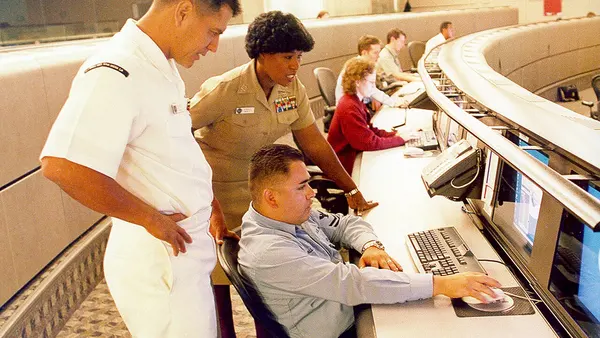 US Navy 040614-N-7952W-001 Information Systems Technician 1st Class Thomas Dull, left, Lt. Stella Nealy, center, and Information Systems Technician 2nd Class Eduardo Pallanes study a computer monitor at Naval Network and Space