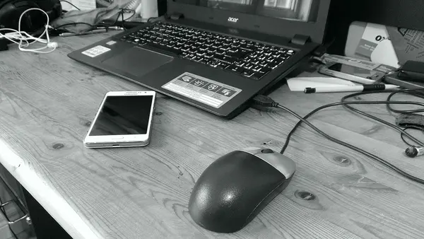 Computer mouse laptop and phone on a desk