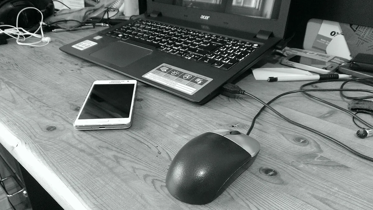 Computer mouse laptop and phone on a desk