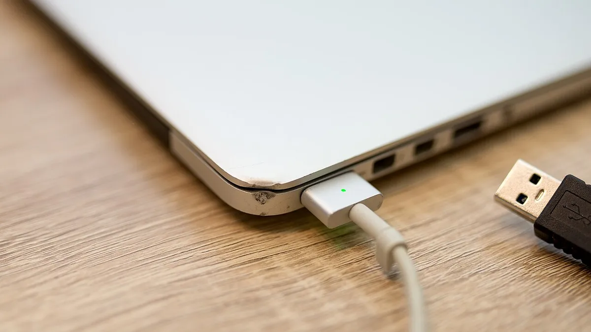 Charging a laptop with a USB cable on a wooden table in a cozy environment during daytime