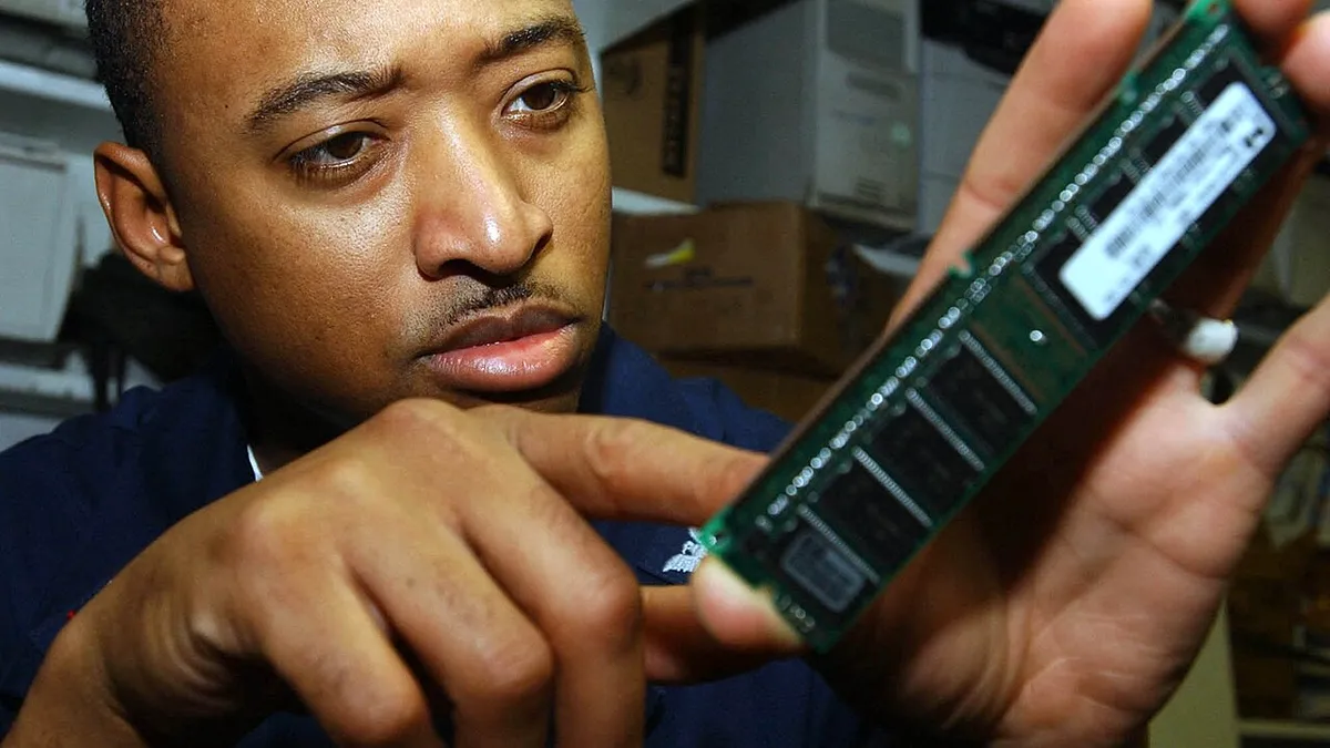 US Navy 050823-N-8119C-136 Electronics Technician 3rd Class Elmarco McNair of Jackson, Miss., inspects a Random Access Memory (RAM) chip aboard the nuclear-powered aircraft carrier USS Nimitz (CVN 68)