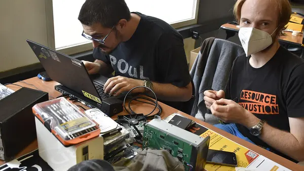 Hackers working on Linux laptop with computer disks and repair kits - Milano 2022