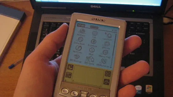 Sony CLIE PEG-S320 held in front of a Dell laptop