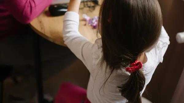 Child playing while parent works on laptop at home during daytime