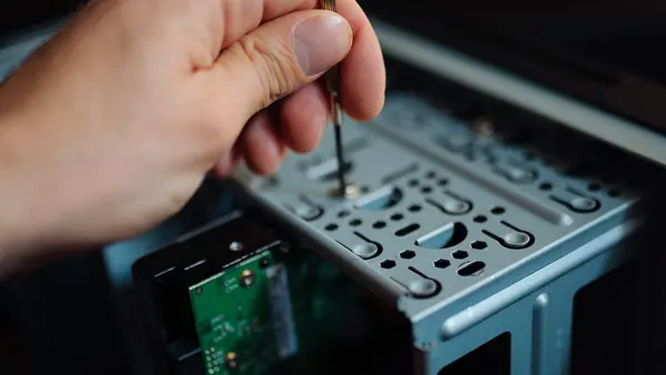 A person is carefully extracting a hard drive from a computer