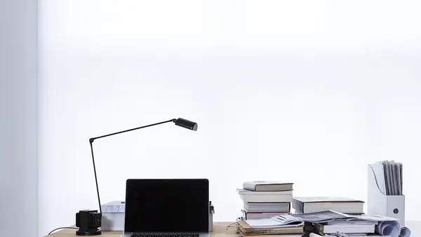 Laptop on desk book stacks (Unsplash)