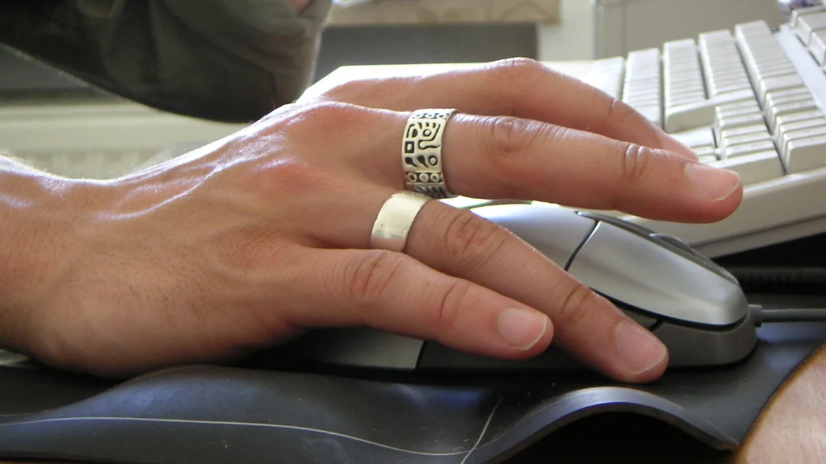 Male hand with two rings operating computer mouse