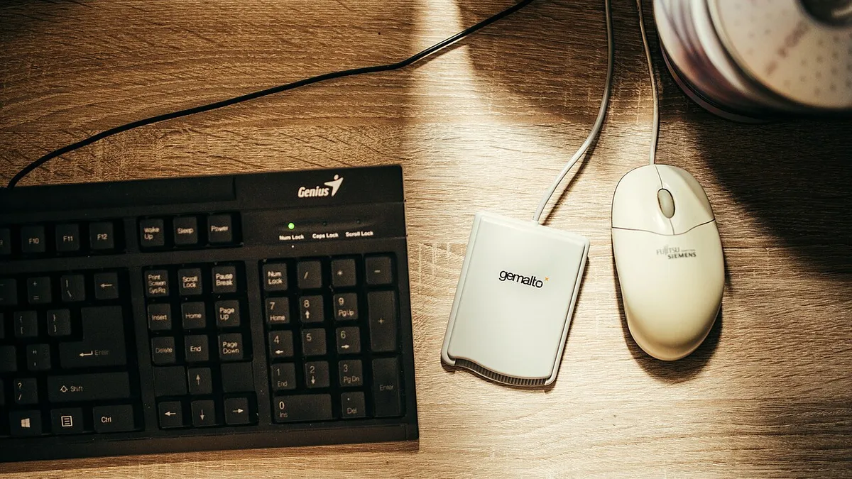 A computer keyboard and mouse are positioned on a wooden des