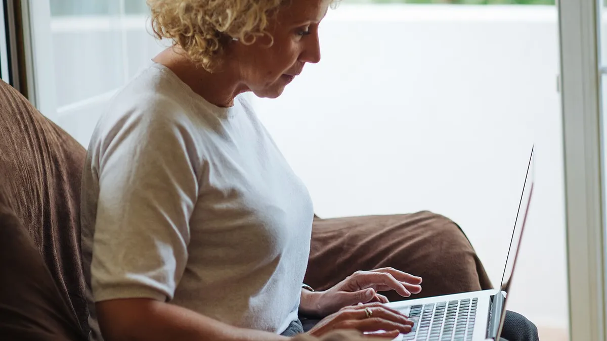 Woman with curly hair typing on her laptop. (51532453225)