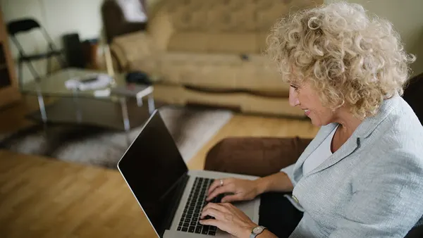 Woman smiling while typing on a laptop. (51533492745)