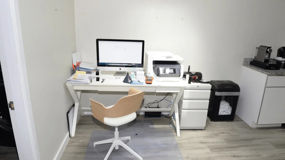 EFTA00002091 - Modern white desk with a computer printer and chair in a minimalist office space