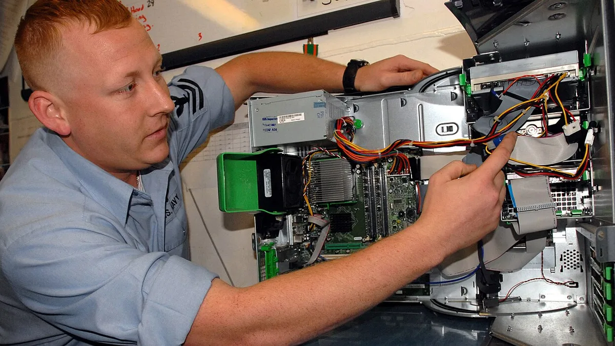 US Navy 060322-N-0555B-034 Information Systems Technician 1st Class Chris Hedger inspects the internal components of a computer during Information Security (INFOSEC) training
