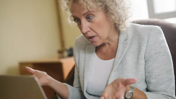 Woman looking confused while sitting in an armchair with a laptop in her lap. (51535516007)