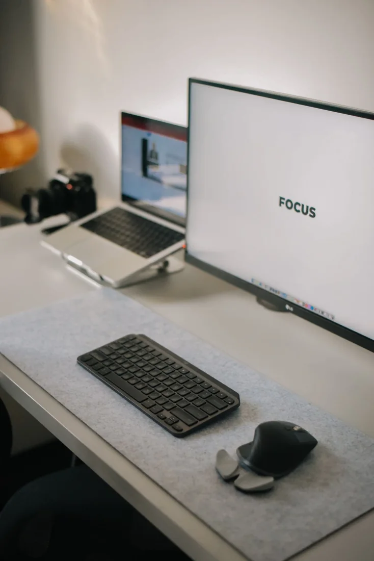 A desktop monitor, laptop and keyboard on an organised desk