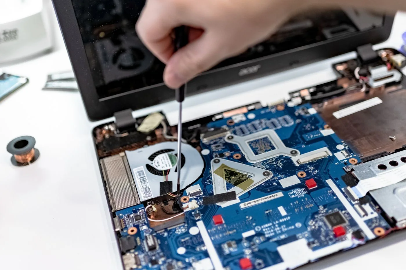A hand using a screwdriver inside an open laptop