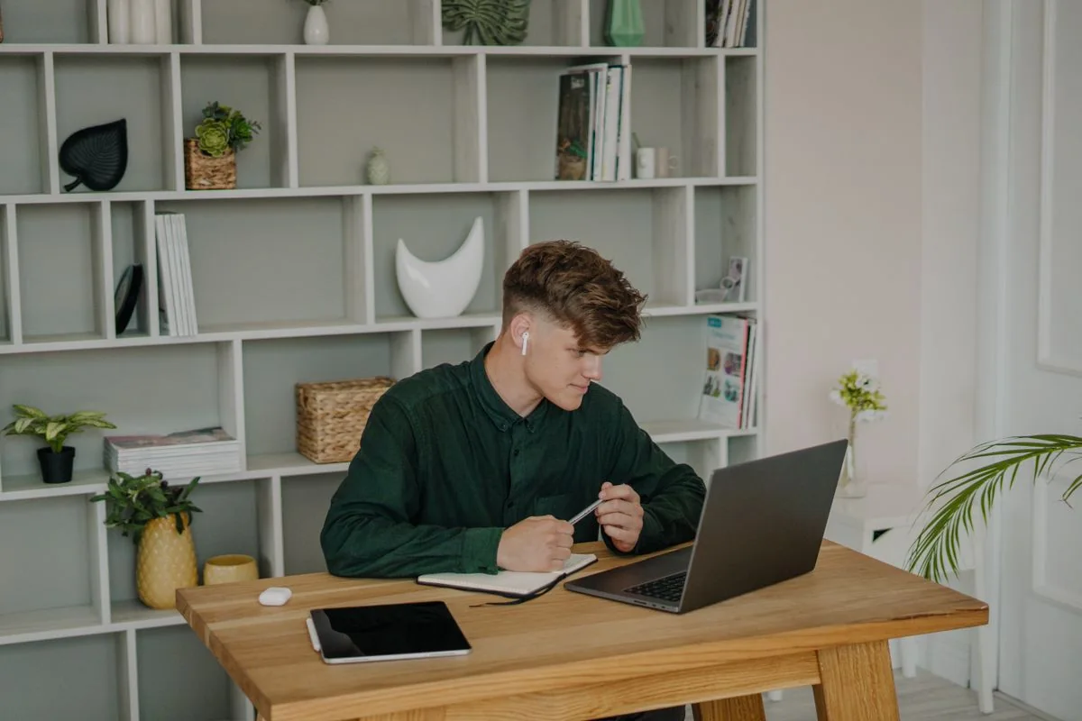 A student using a laptop at a wooden desk